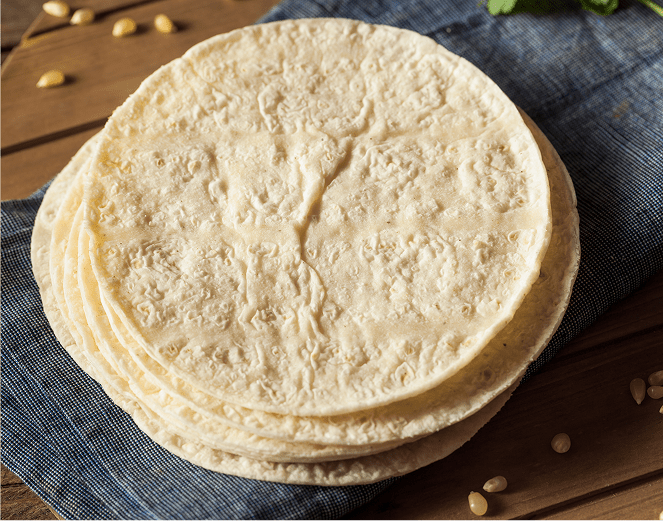 Round flour tortillas stacked on denim napkin